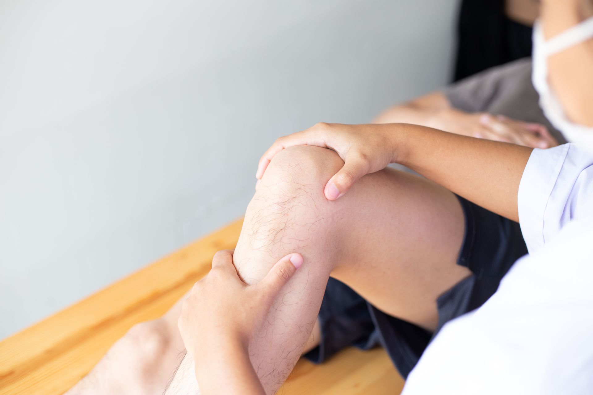 Person applying cream to a bent knee during a physical exam or therapy session