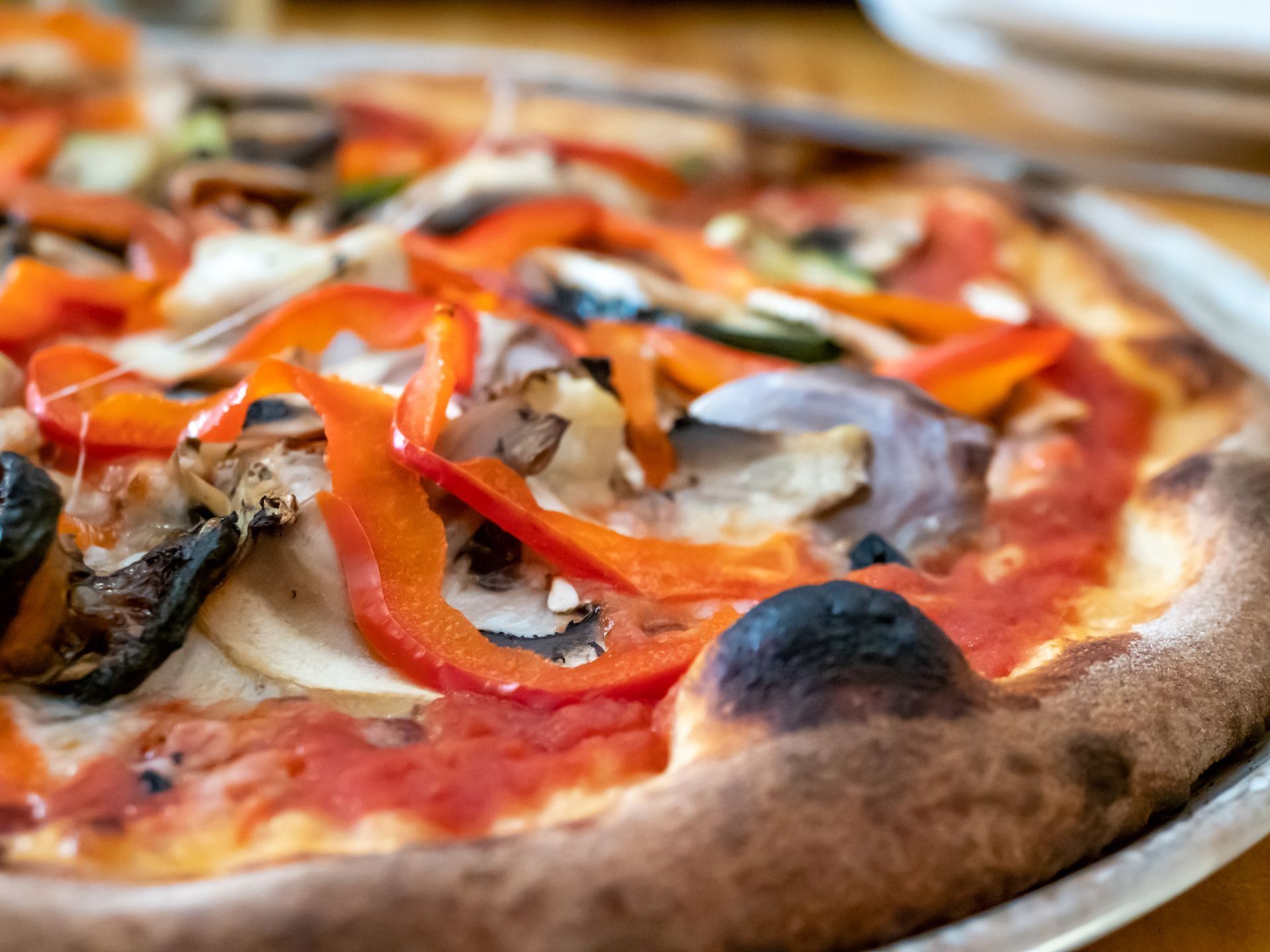 Pizza con peperoni rossi, cipolle, funghi e salsa di pomodoro; primo piano.