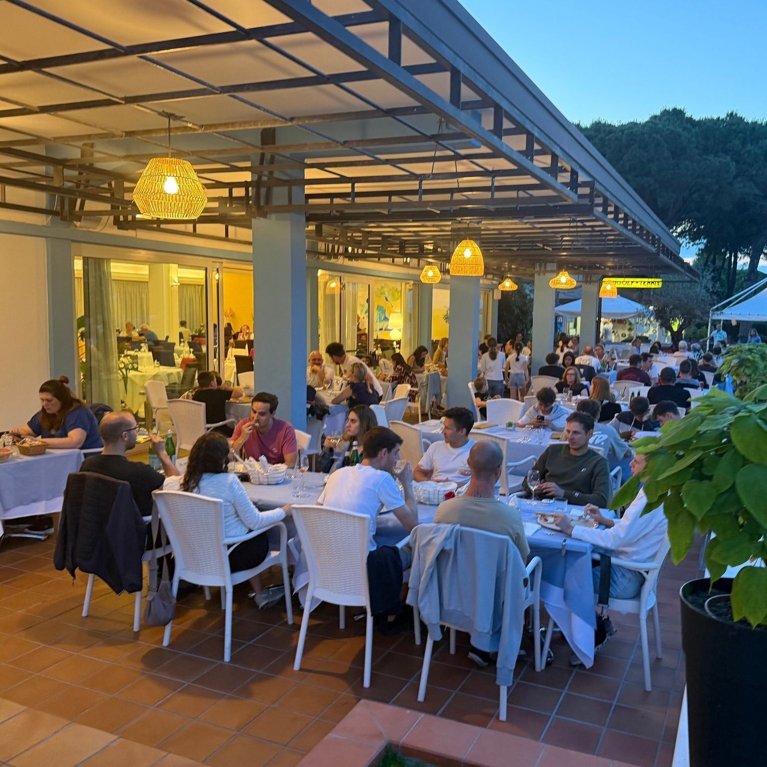 Sala da pranzo del ristorante con tavoli apparecchiati per il servizio, con vista sul soleggiato giardino.