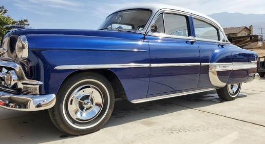 Blue and white classic Chevrolet car with chrome accents parked outdoors.