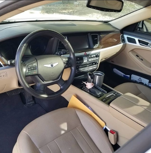 Interior of a car with beige leather seats, black steering wheel, and wooden trim.
