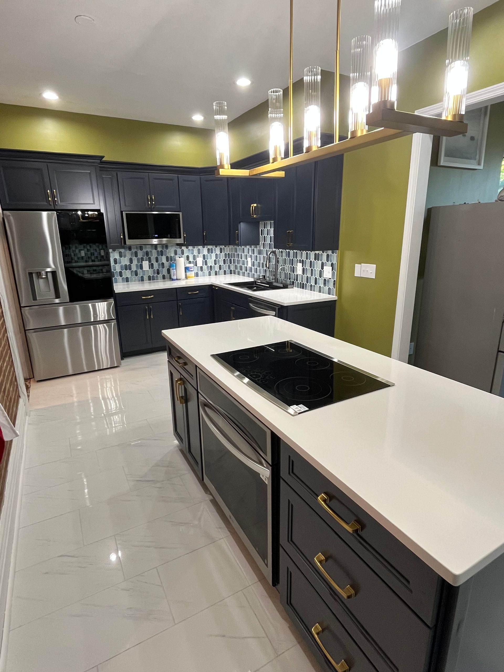 Bright white kitchen with marble island, pendant lights, wood floors, and adjacent dining area