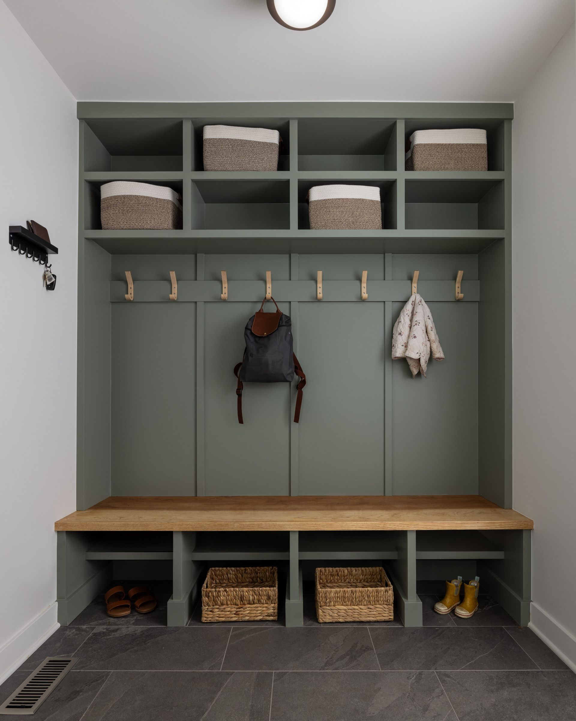 Warm-lit walk-in closet with wood shelves, hanging rods, drawers, and a built-in bench.