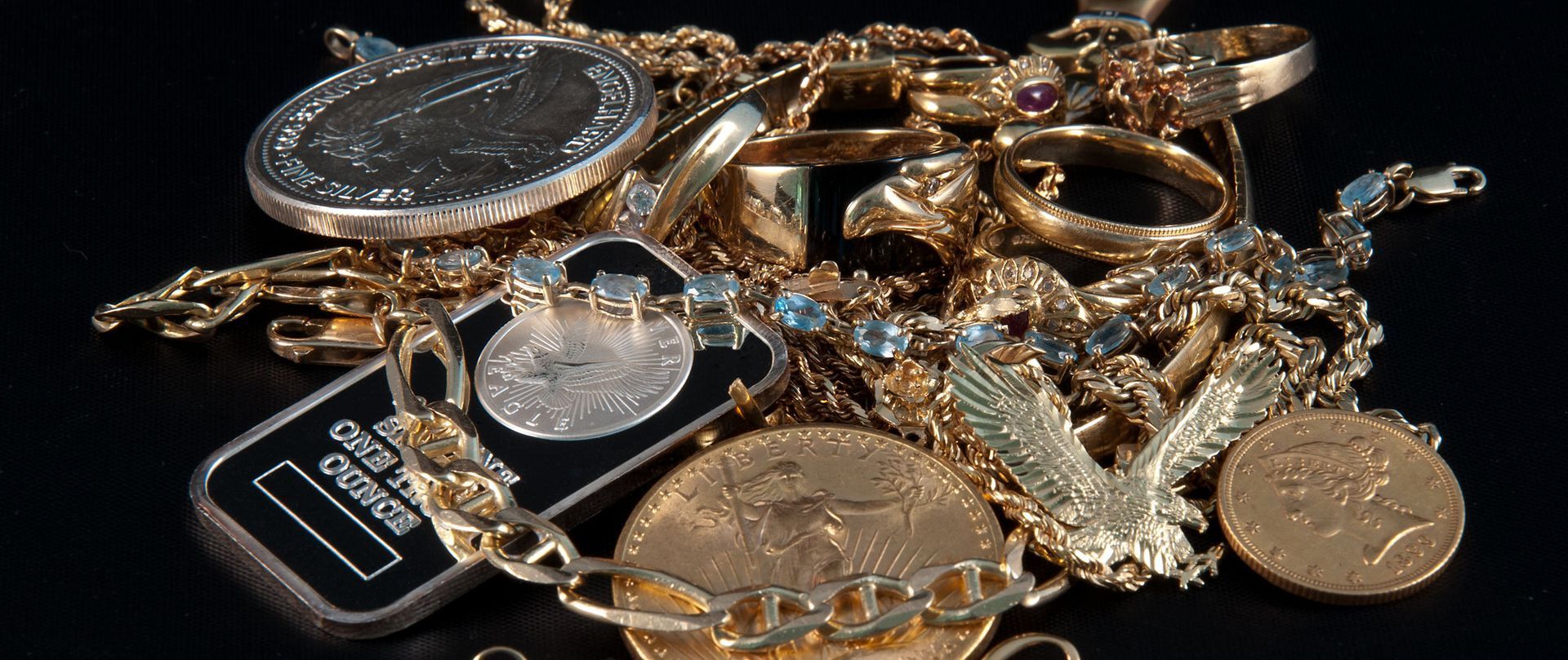 Assorted gold and silver jewelry pieces piled together on a dark surface