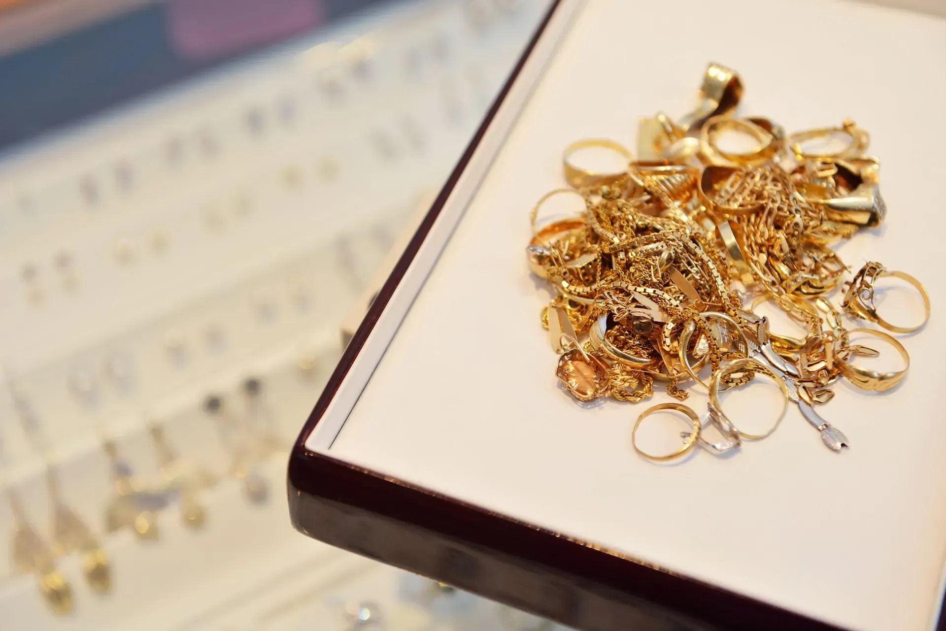 Pile of gold rings on a white display tray in a jewelry store display case