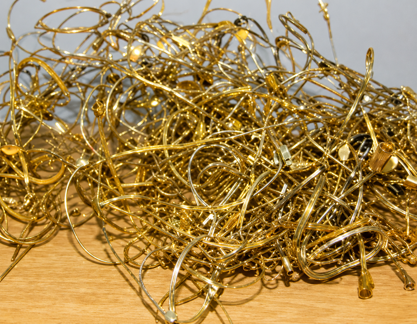 A tangled pile of shiny gold metallic wire scraps on a wooden surface