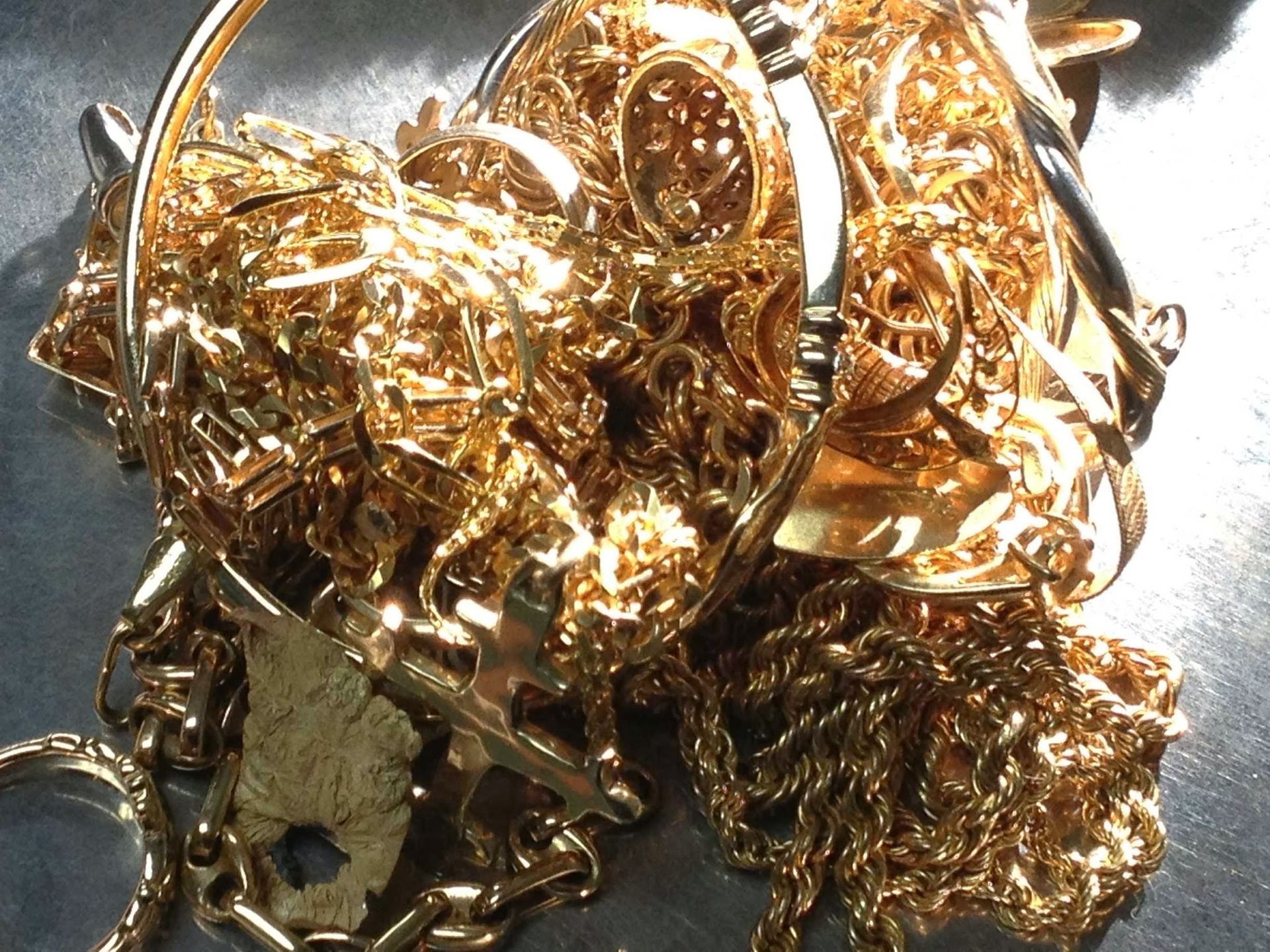 Pile of tangled gold jewelry and chains on a white background