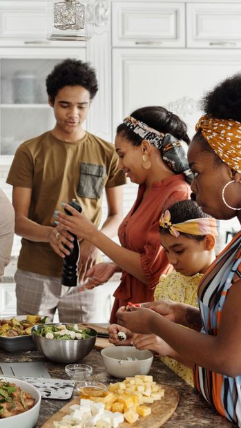 A group of people cooking and preparing food together in a bright kitchen.