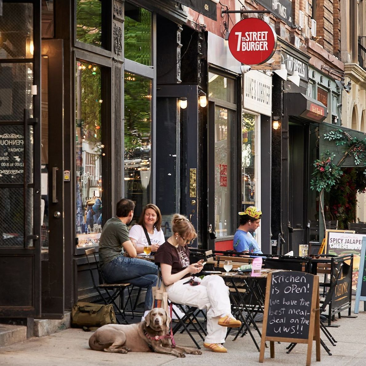 People are sitting outside a restaurant called 7th street burger