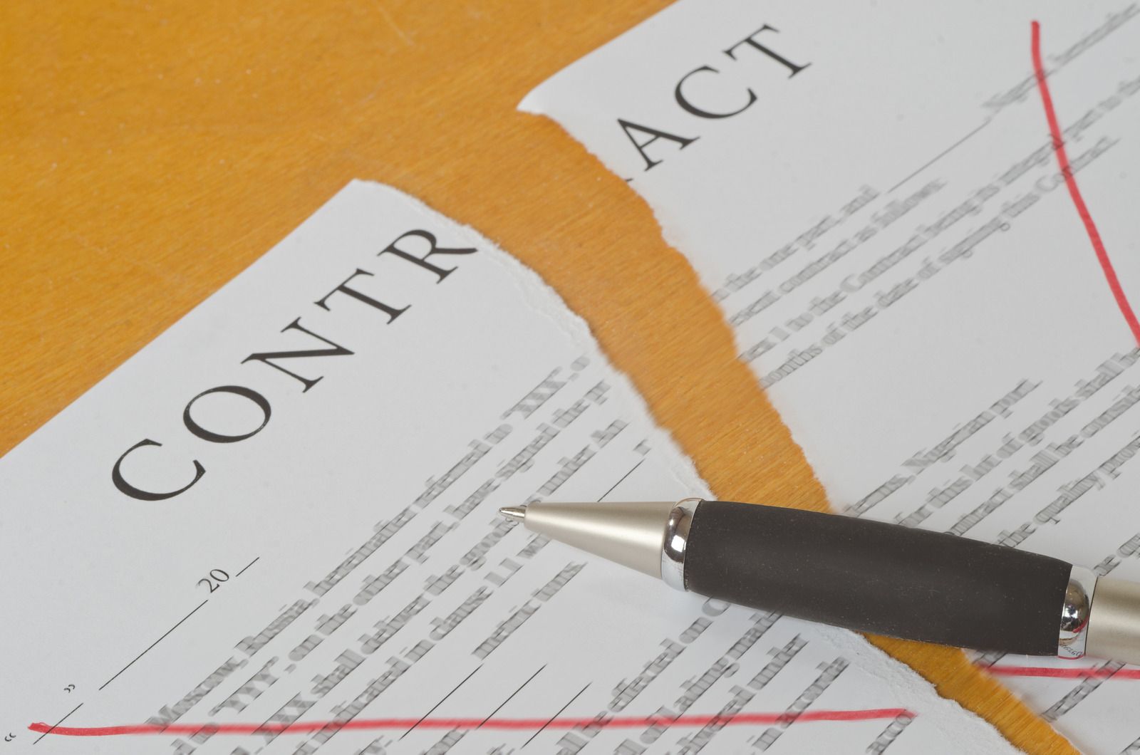 Broken contract document with a pen on a yellow surface