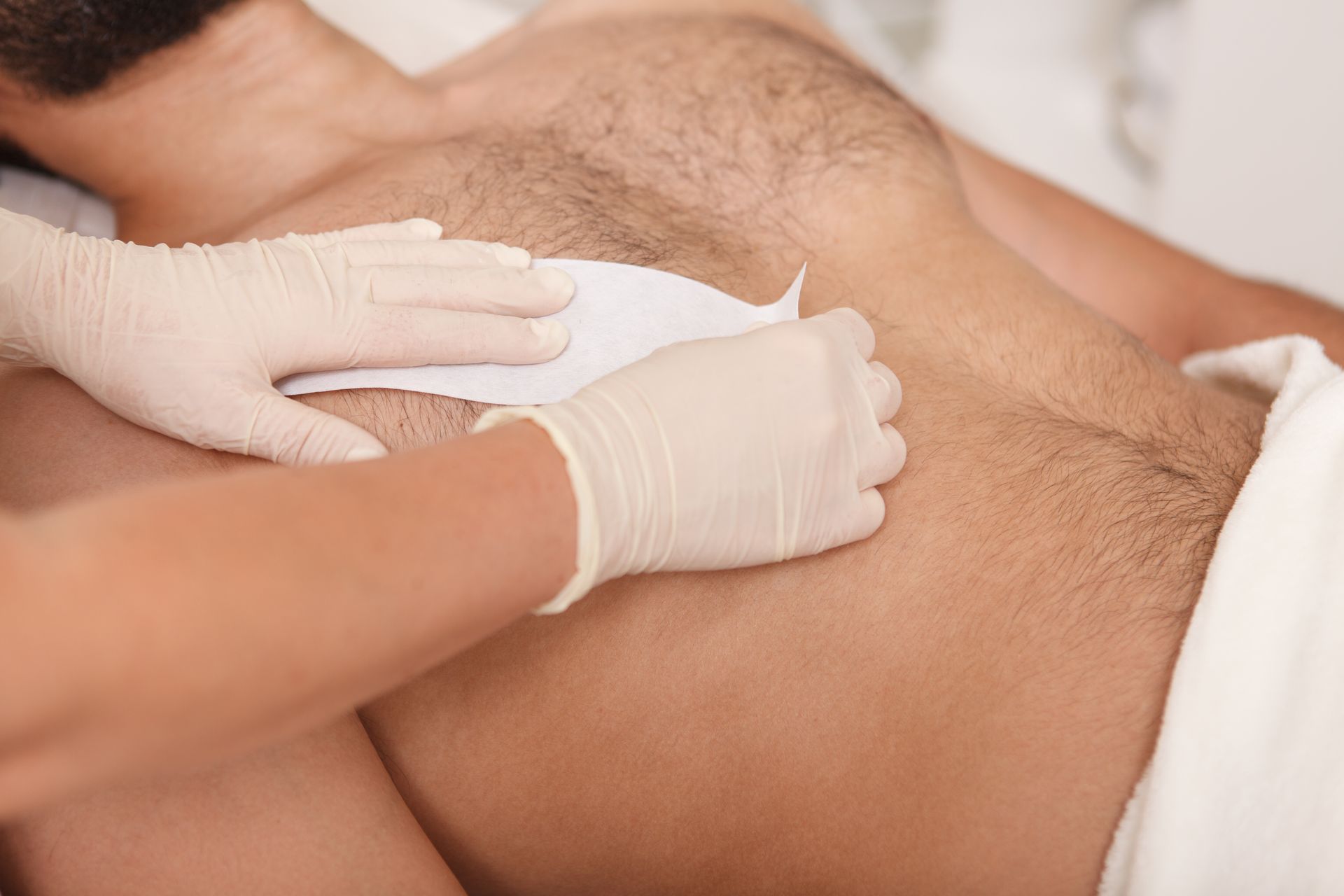 A man is getting his chest waxed by a woman.