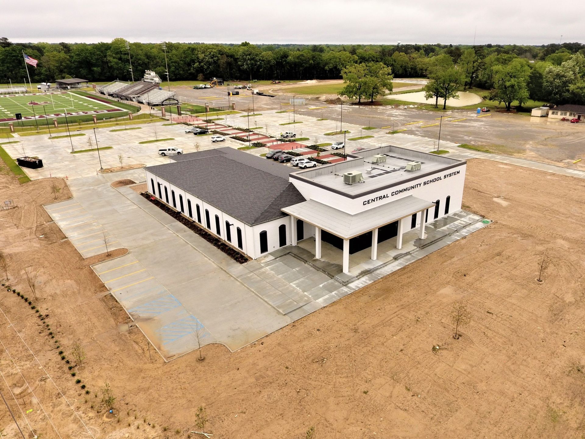 Aerial view of a small building complex with parking lots and roads on a barren hillside.