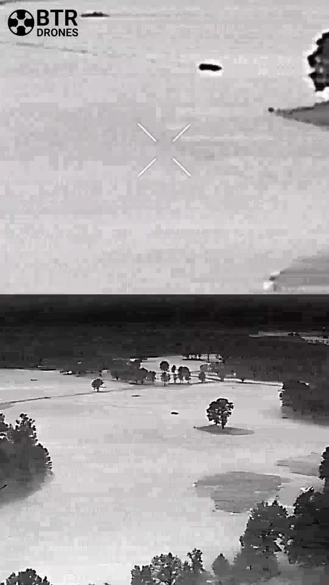 Thermal view of a flooded landscape with trees and scattered structures under a dark sky.