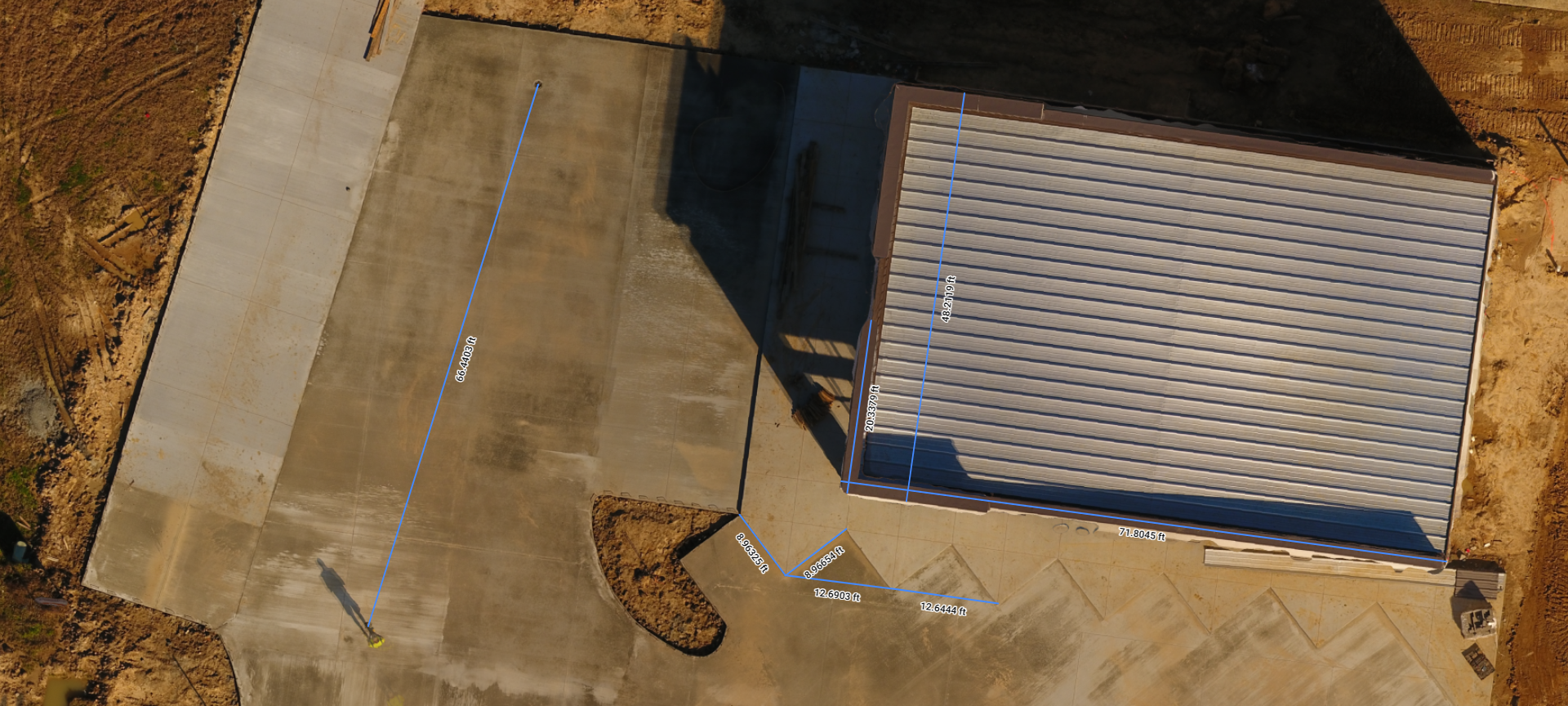 Aerial view of a tan rooftop beside a concrete area and a small curved path