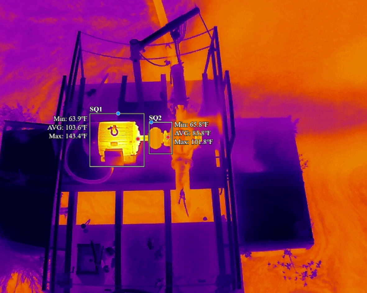 Thermal view of an industrial structure with pipes, tanks, and a bright hot spot against a purple-orange background