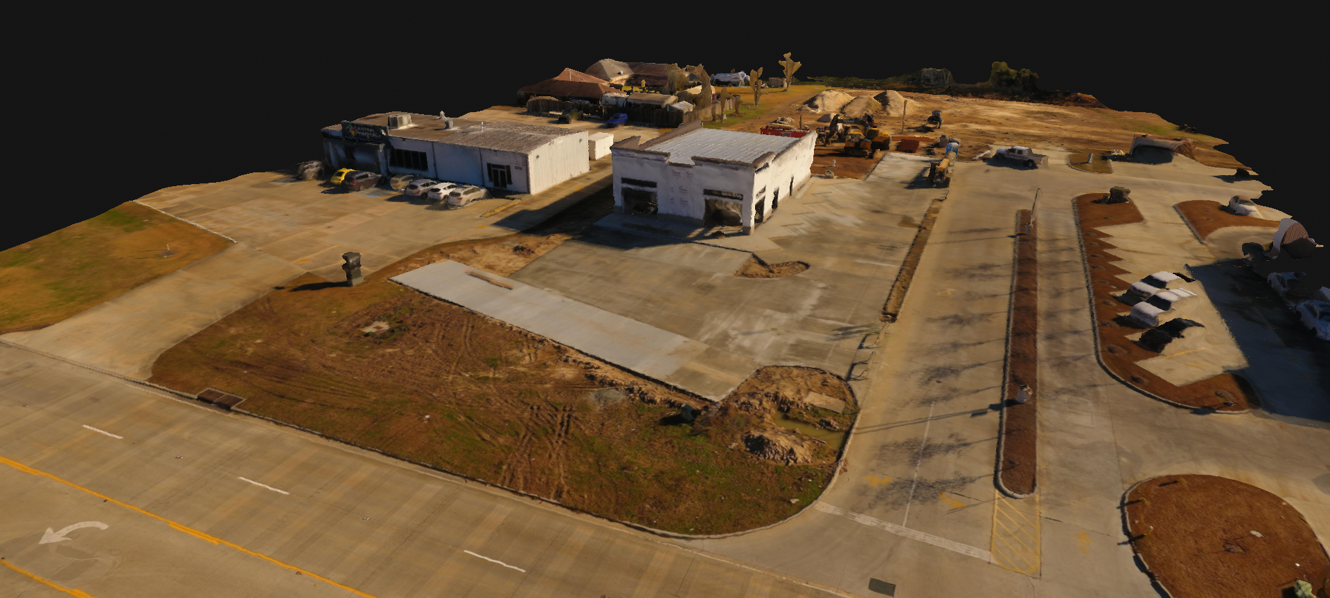 Aerial view of a small building complex with parking lots and roads on a barren hillside.