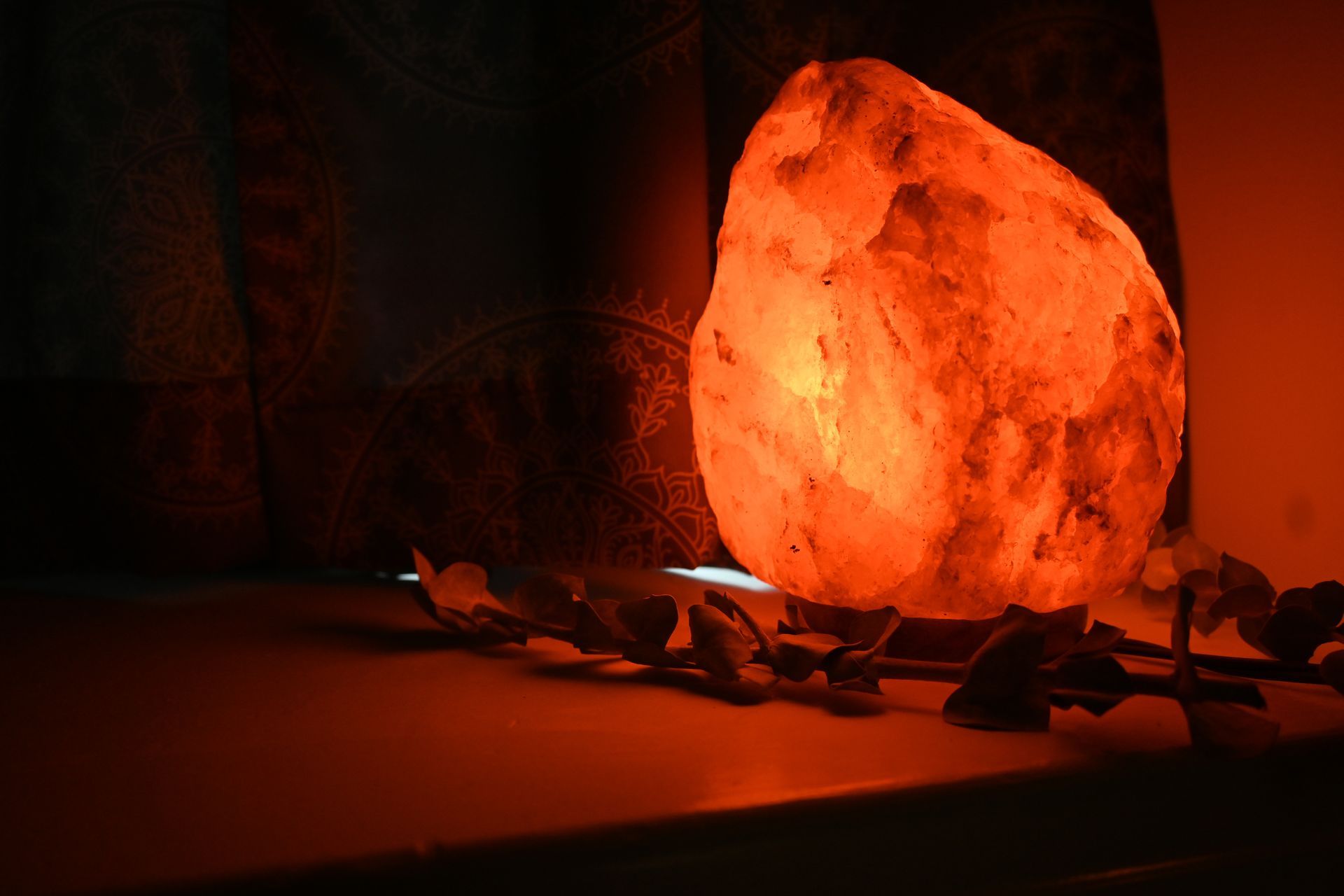 A large rock lamp is sitting on a table next to a rose.