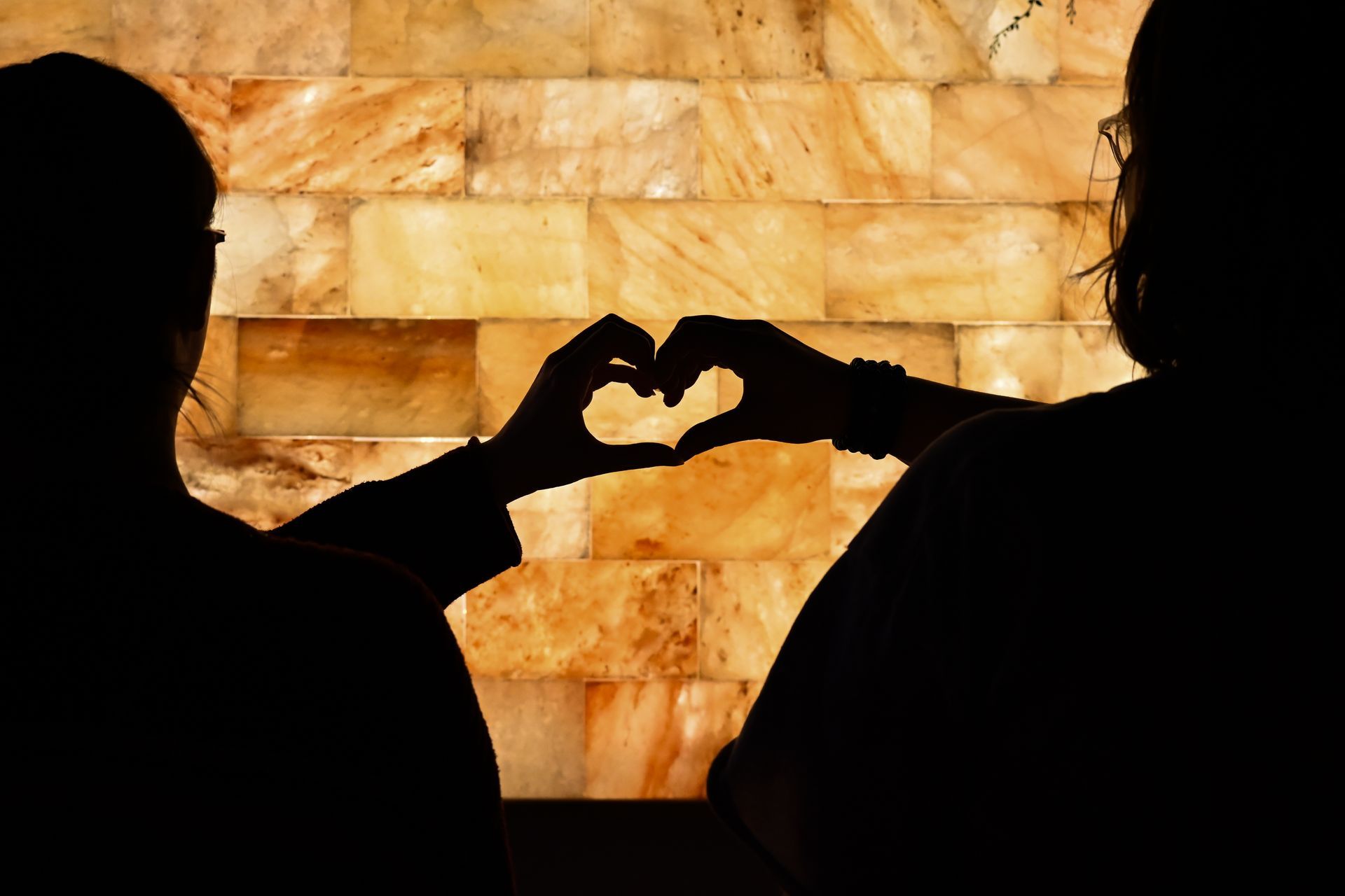 Two people are making a heart shape with their hands.