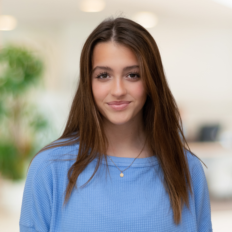 A young woman in a blue sweater is smiling for the camera.