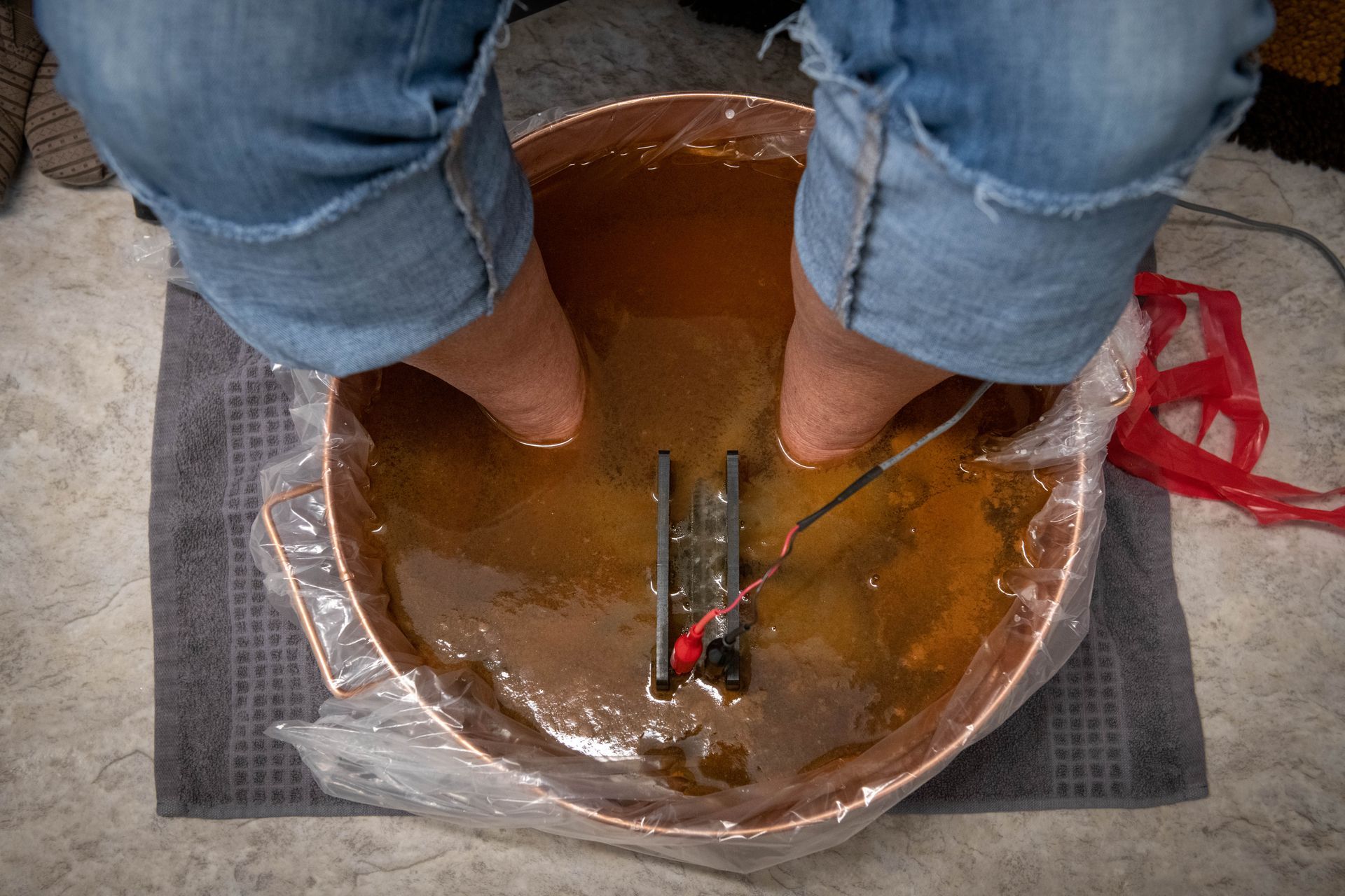 A person is sitting in a bowl of water with their feet in it.