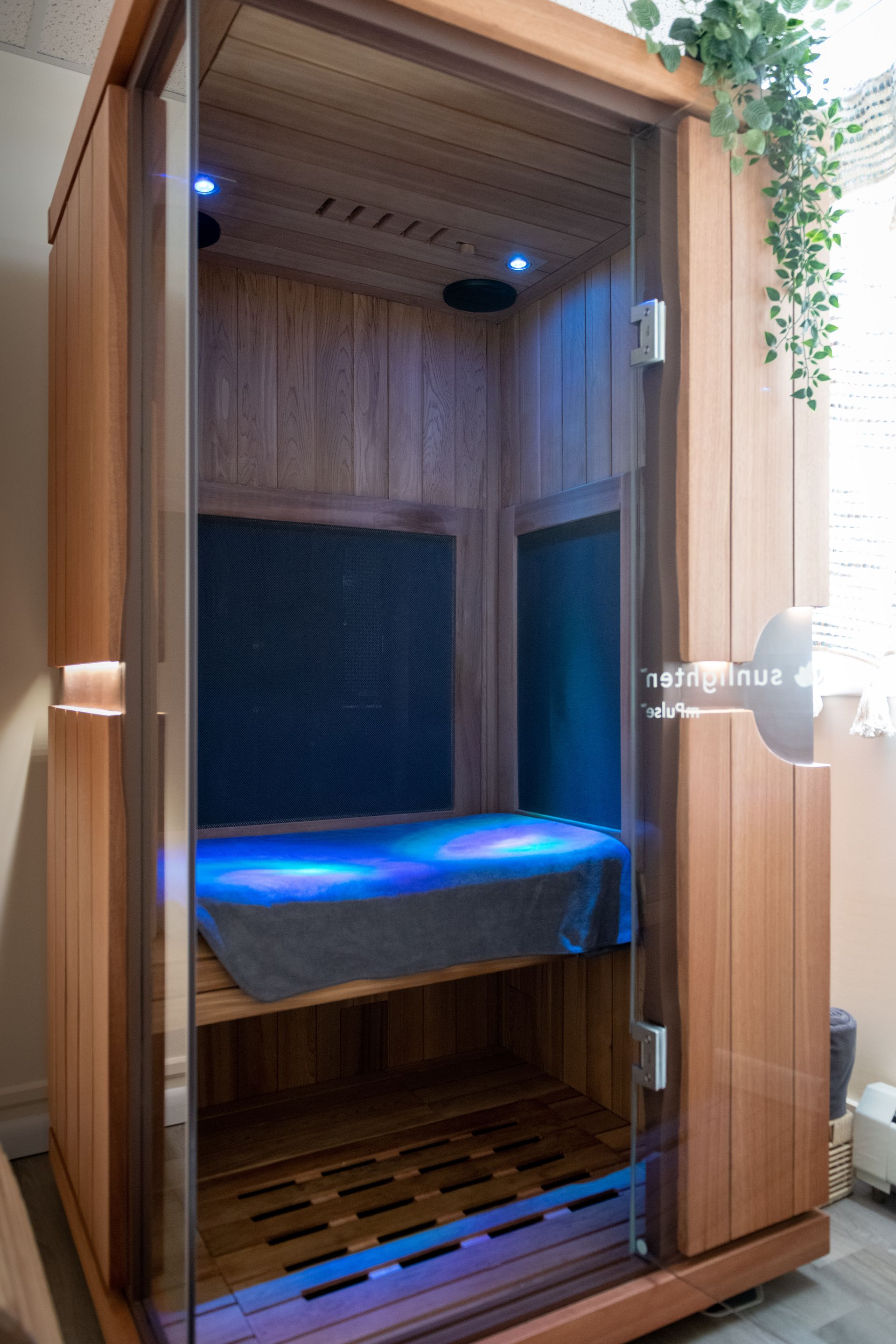 A wooden sauna with a glass door is sitting in a room.