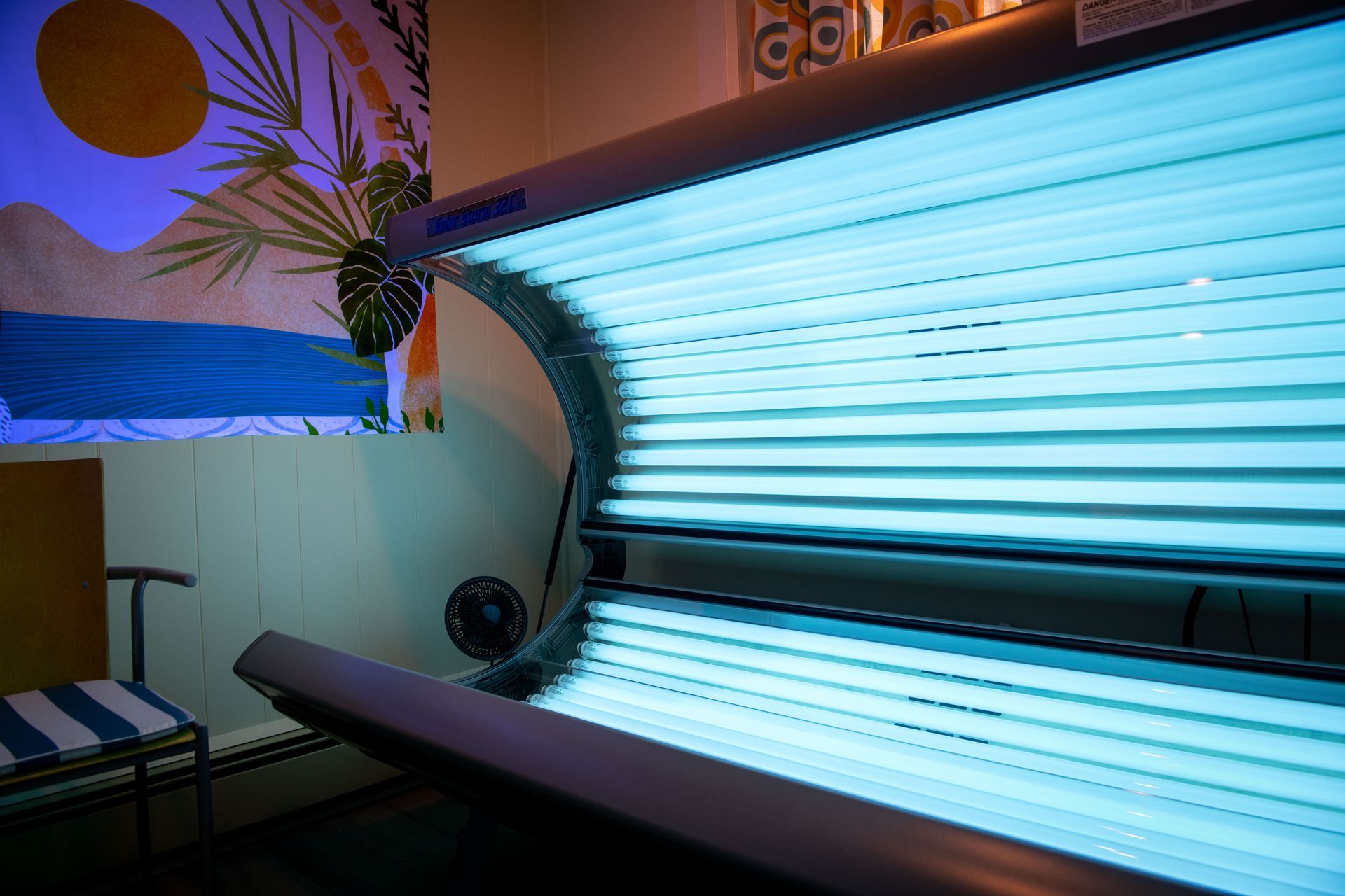 A tanning bed is sitting in a room with a painting on the wall.