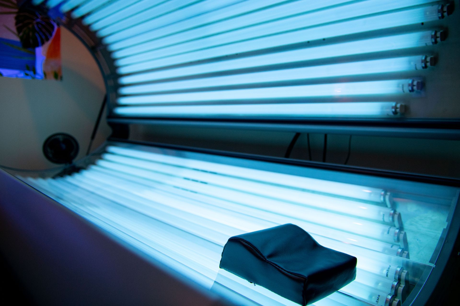 A tanning bed with blue lights and a chair in it.