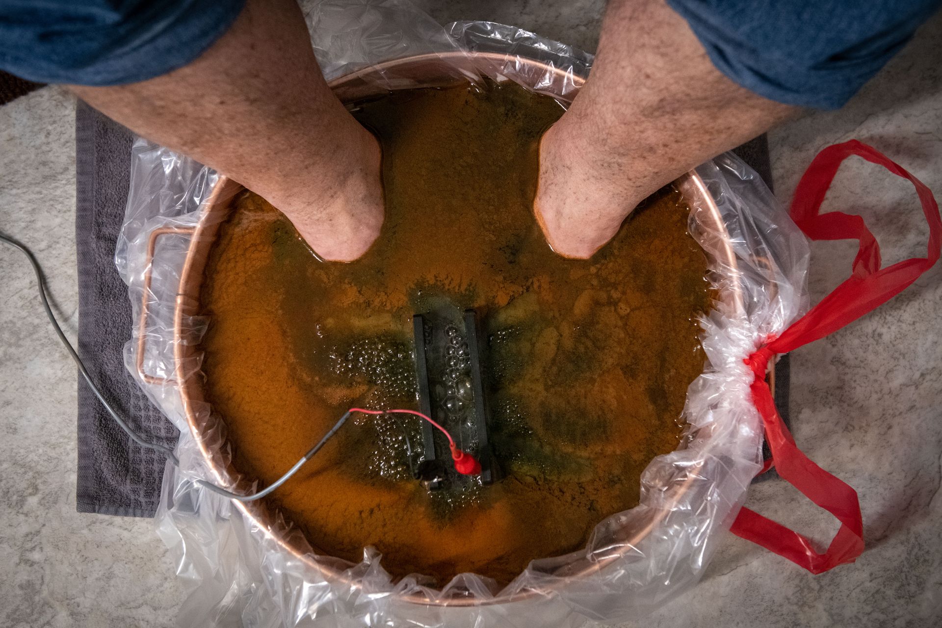 A person is washing their feet in a bowl of water.