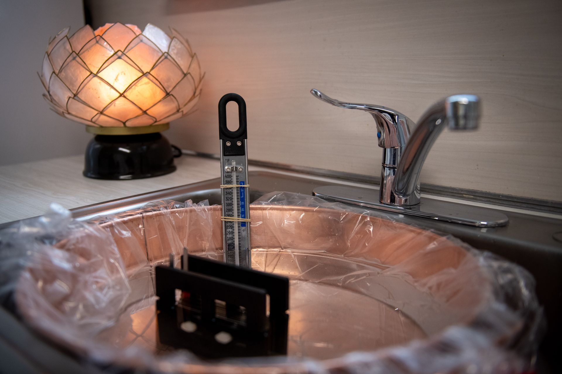 A sink with a trash bag in it and a lamp in the background