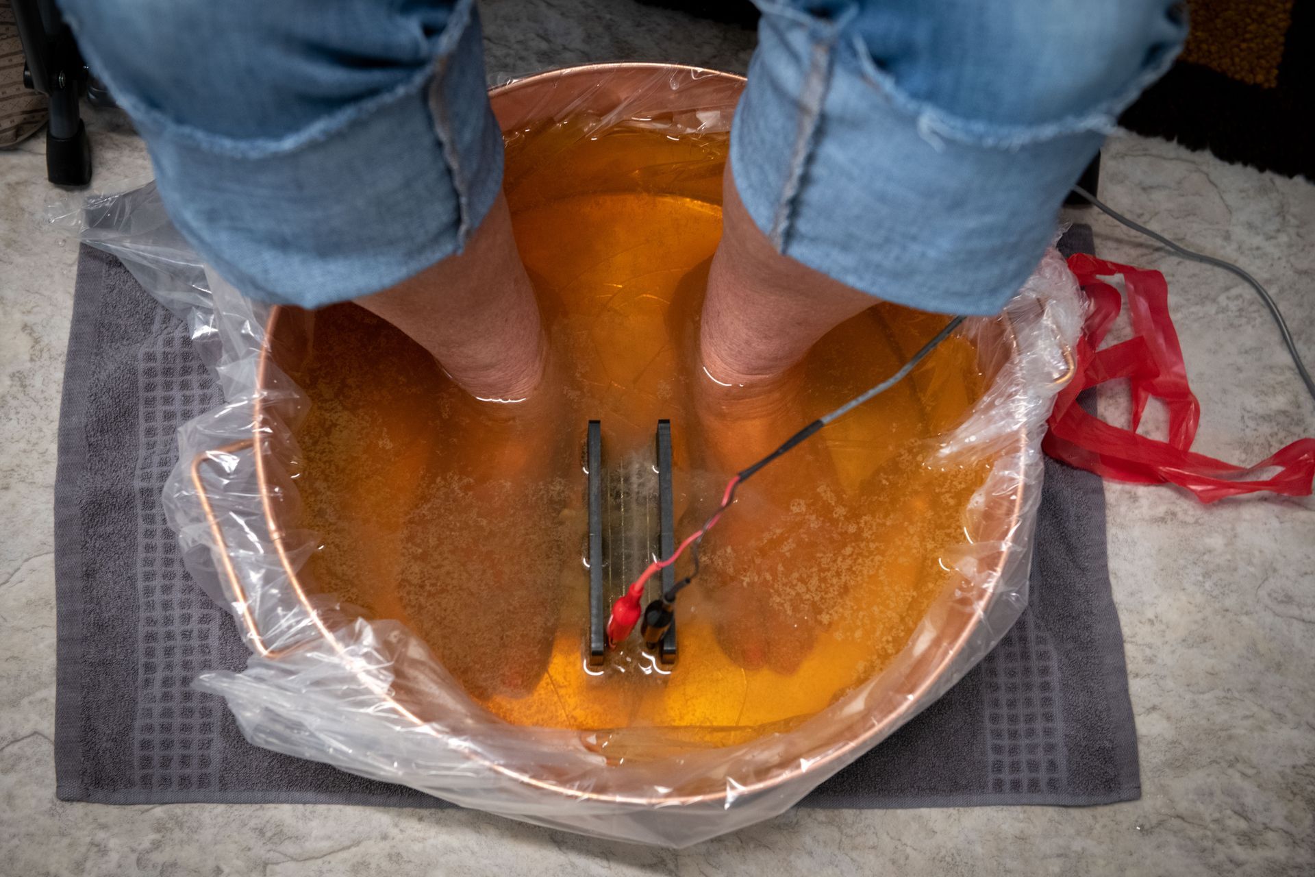 A person is sitting in a bowl of water with their feet in it.
