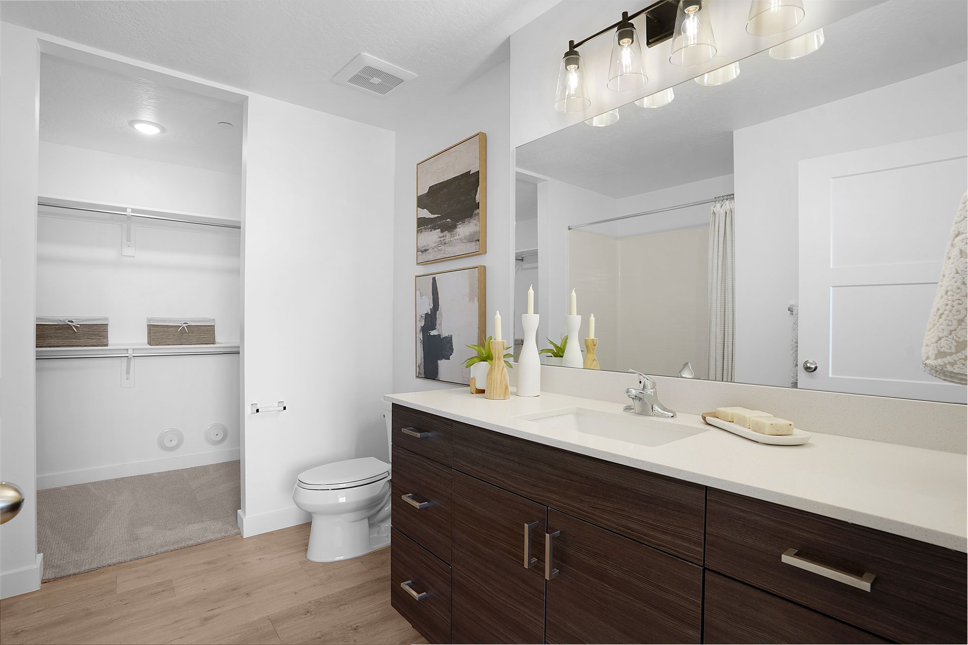 Bathroom with dark wood vanity, white countertops, mirror, and walk-in closet at Sorella in Herriman, UT.
