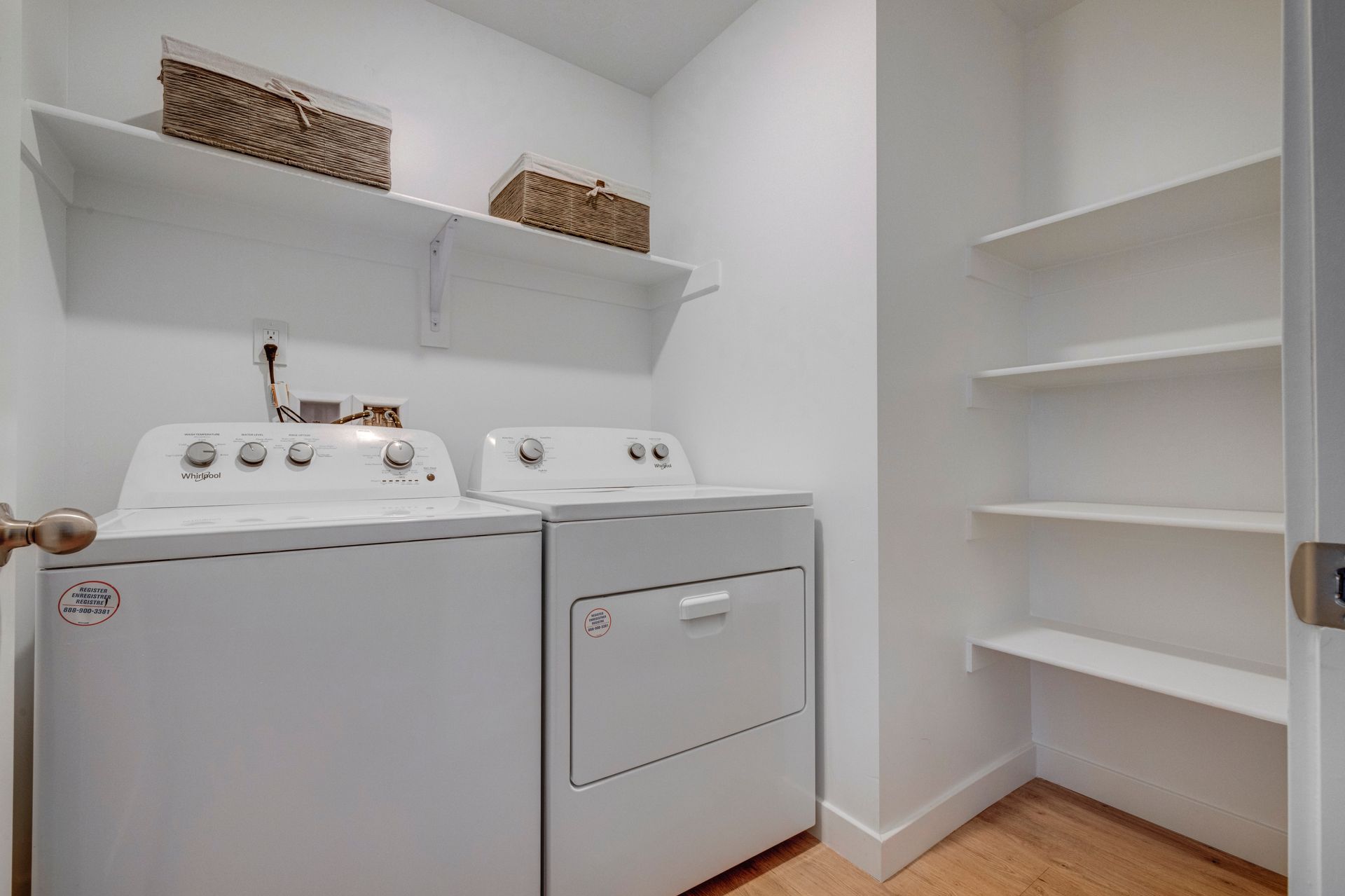 Laundry room with white washer, dryer, shelves, and woven baskets at Sorella in Herriman, UT.