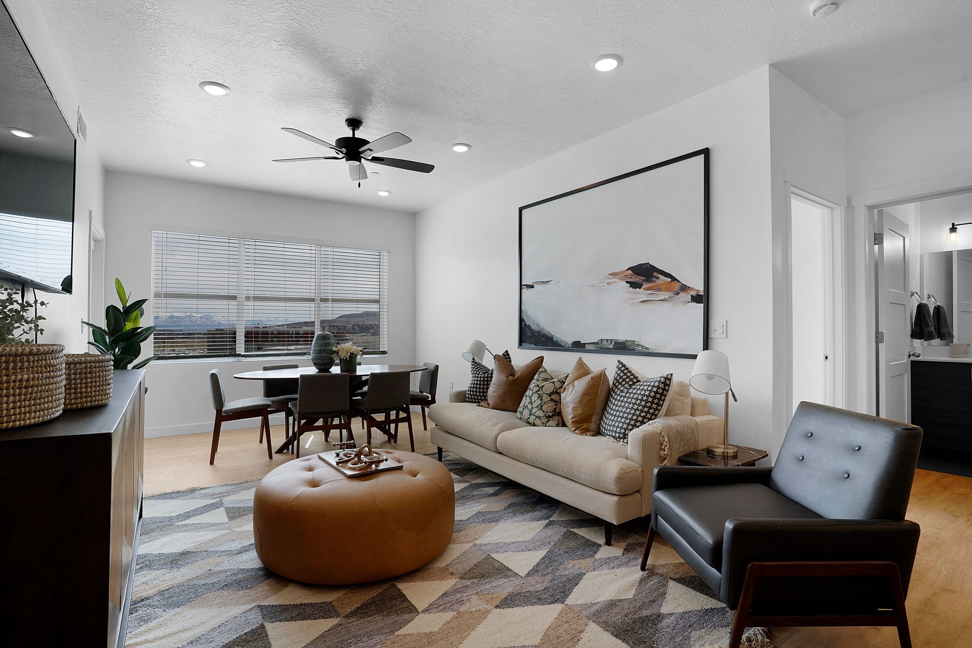 Living room with dining area, neutral colors, modern furniture, and large abstract art at Sorella in Herriman, UT.