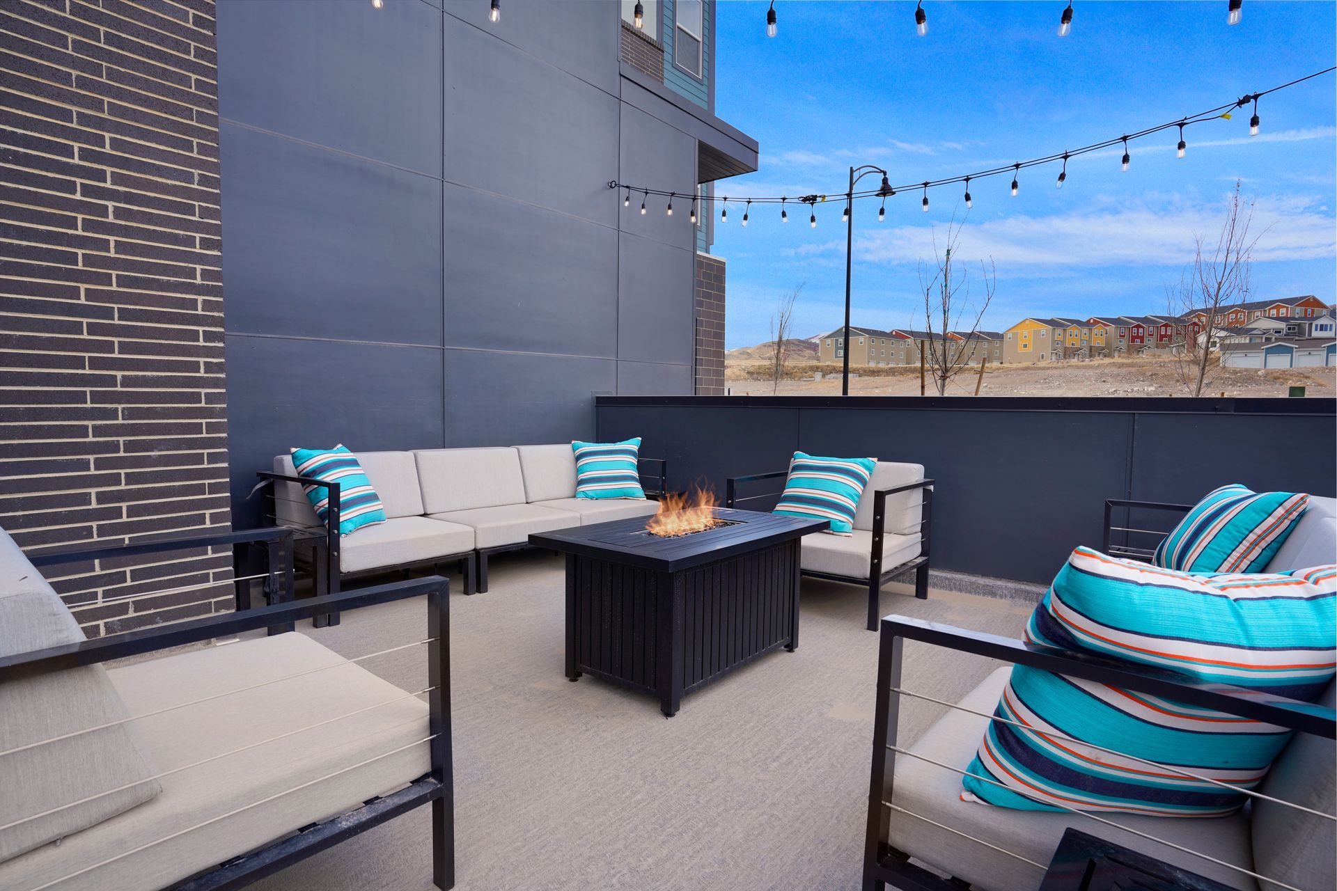 Outdoor patio with seating, fire pit, and string lights against a blue sky at Sorella in Herriman, UT.