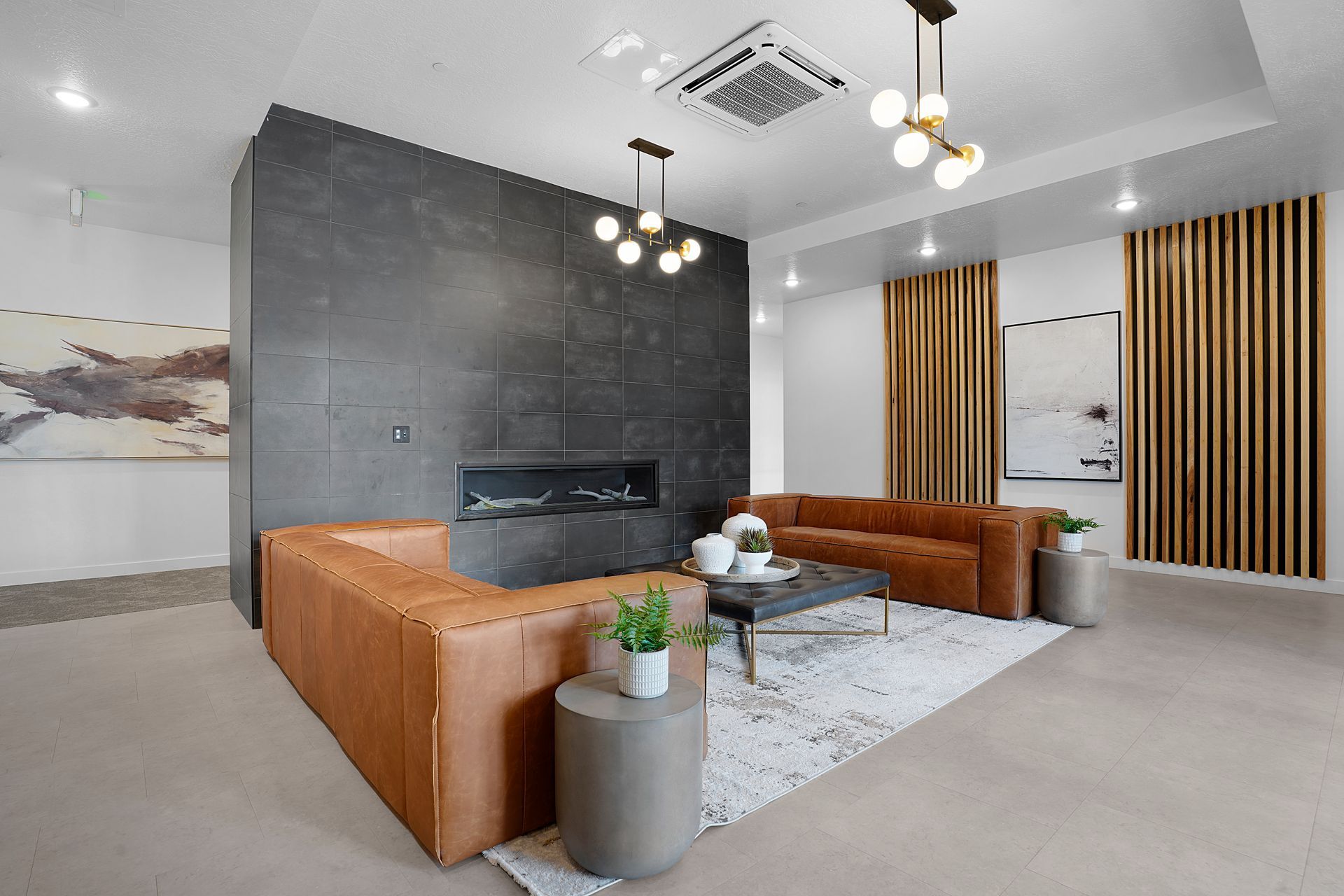 Modern living room with a brown leather sectional sofa, fireplace, and wooden accents at Sorella in Herriman, UT.