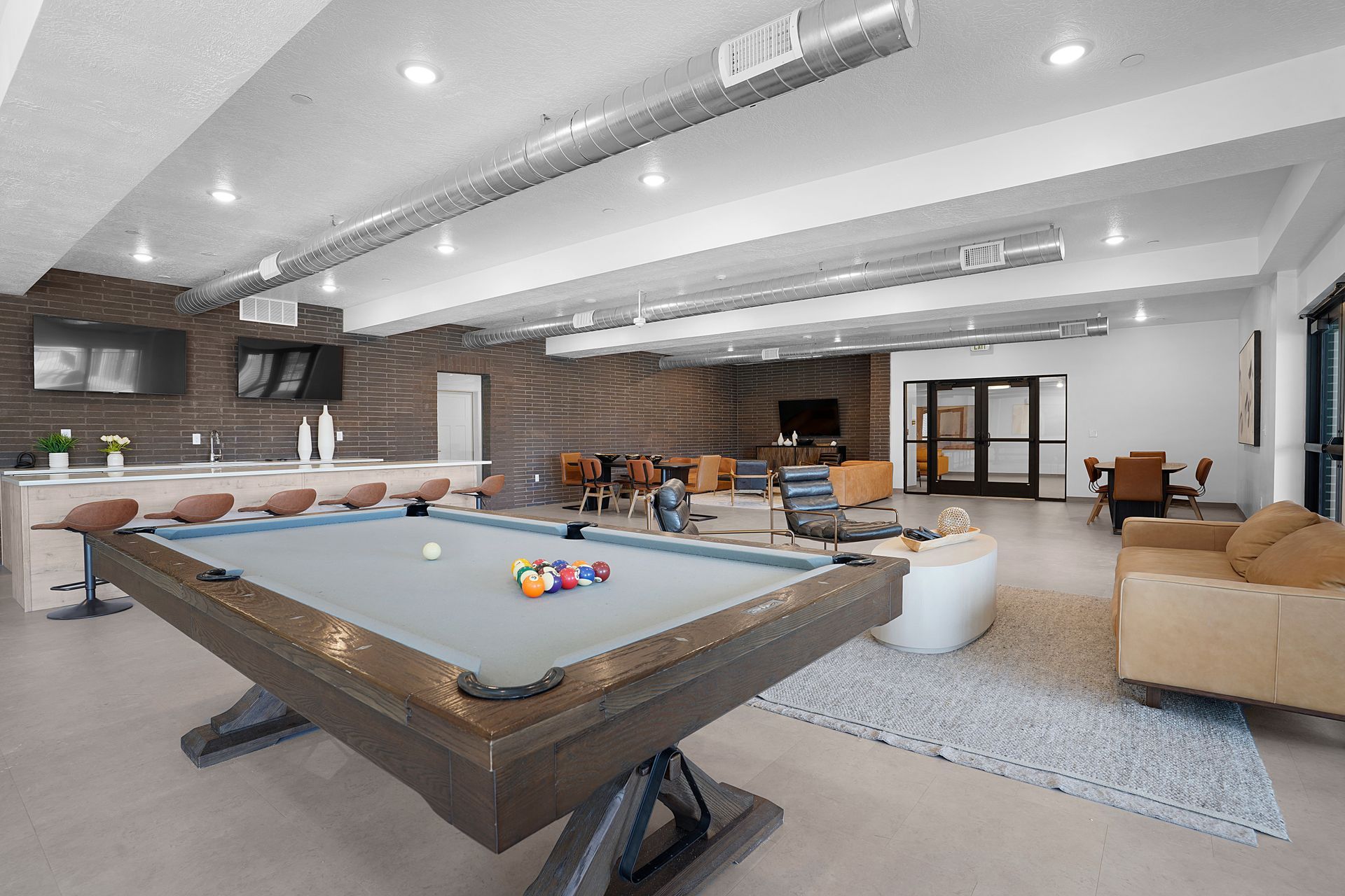 A recreational room with a pool table, bar, and seating areas at Sorella in Herriman, UT.