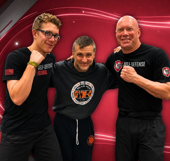 Three people in black shirts pose smiling against a red studio backdrop.