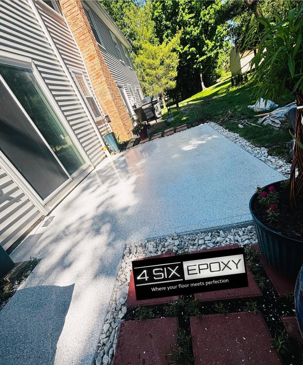 Fresh white epoxy patio beside a house, with a black “SIX EPOXY” sign in the foreground.