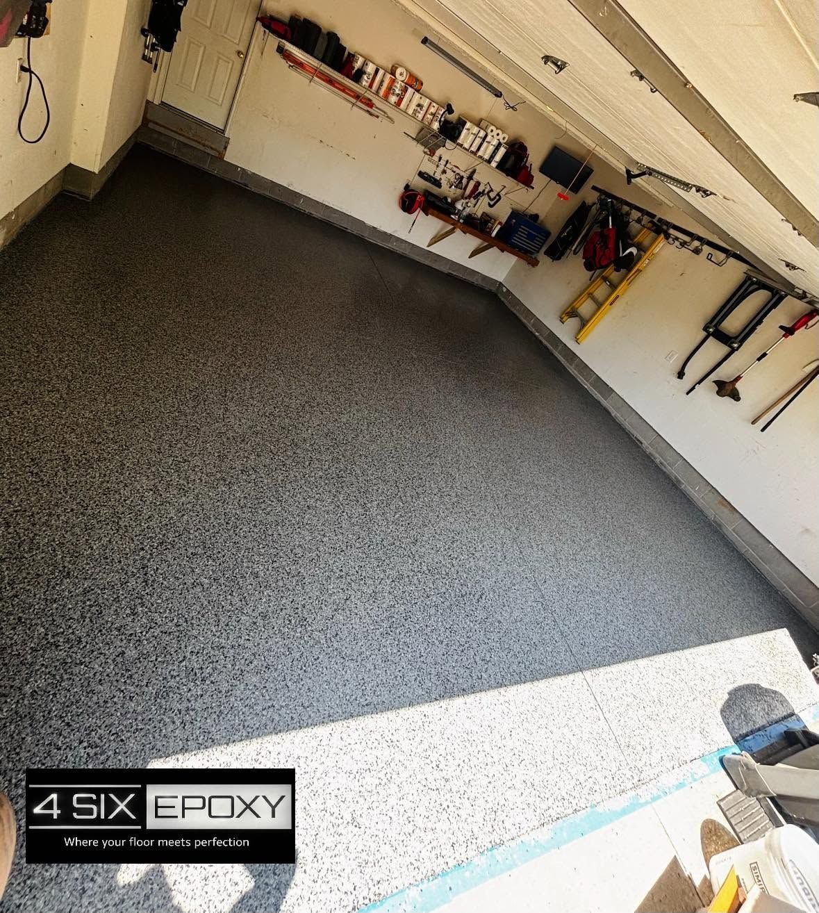 Epoxy-coated garage floor with speckled gray finish and tools hanging on the wall
