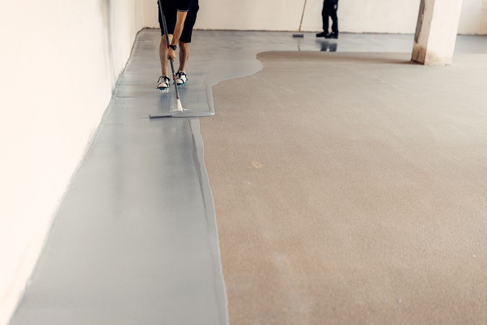 People walking along a narrow gray path beside a tan floor in a large indoor space