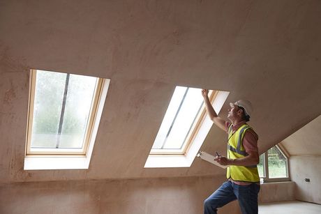 Worker installing skylight windows in an attic with sloped ceiling