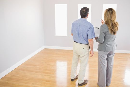 Two people viewing wall art in a bright, empty gallery room