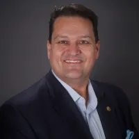 A man in a suit and tie is smiling for the camera