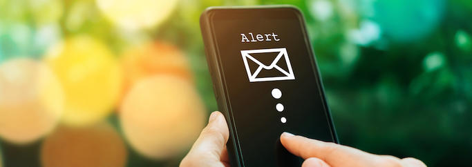 A person is holding a cell phone with an envelope on the screen.