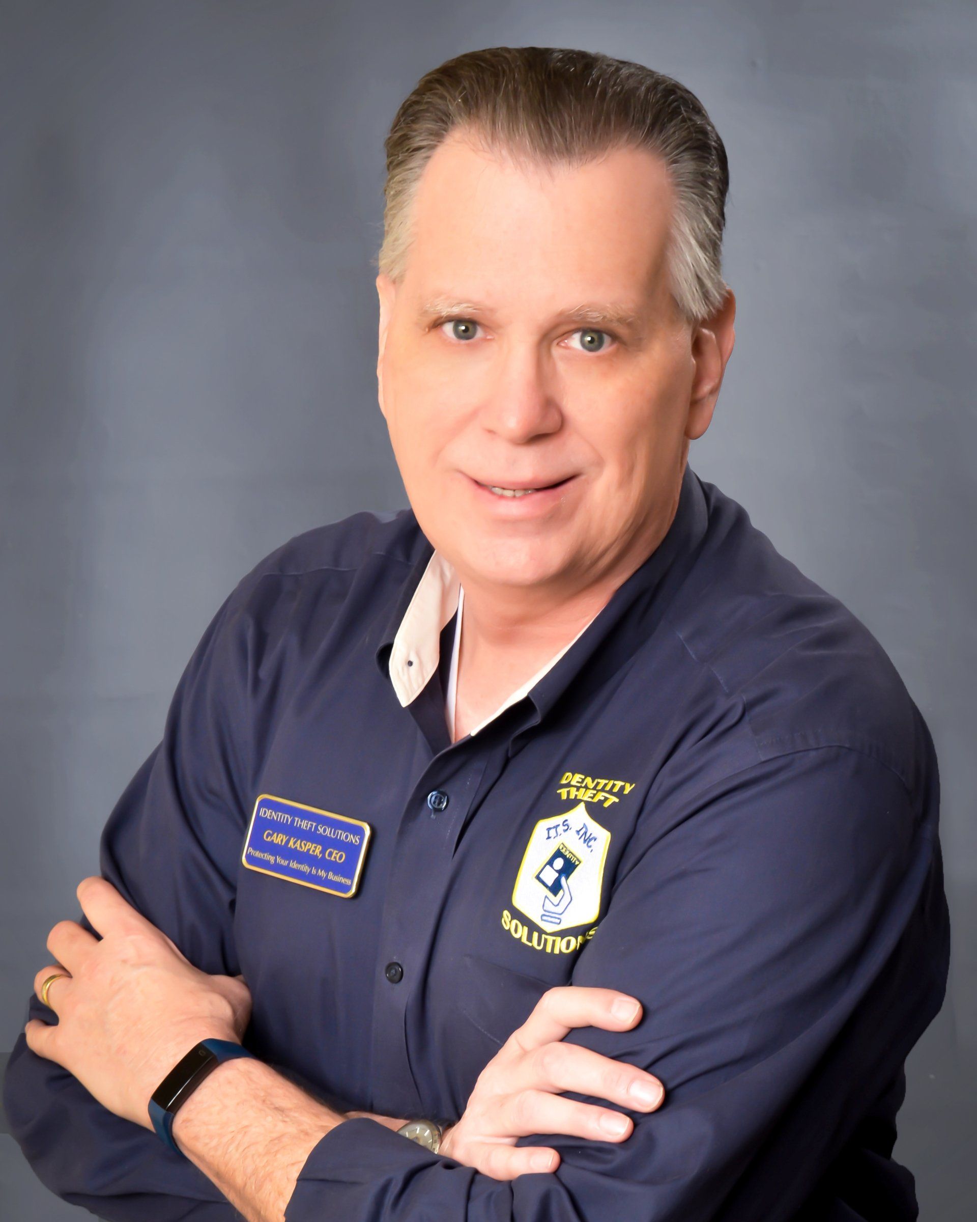 A man with his arms crossed wearing a blue shirt with a patch on it