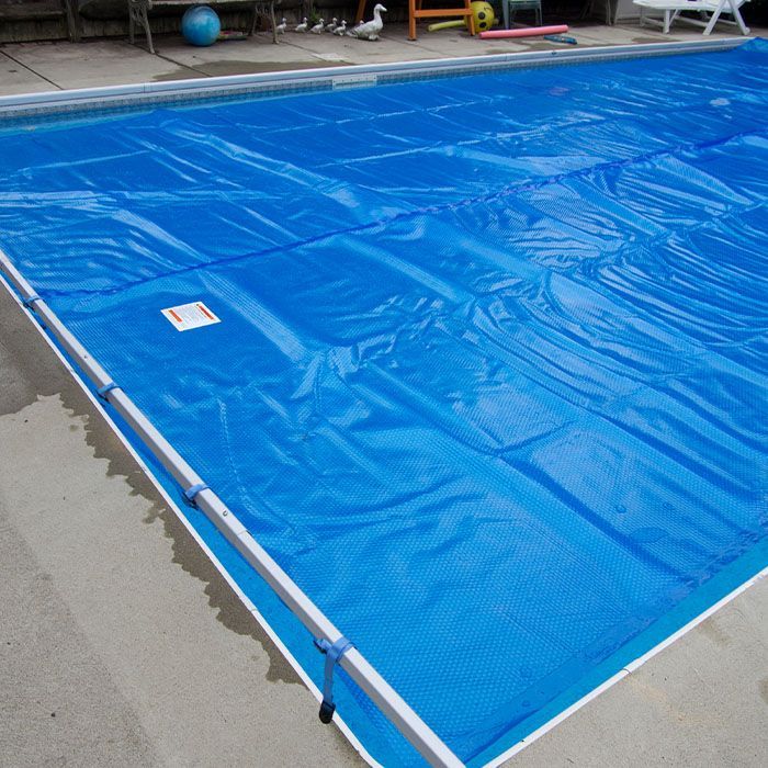 Covered swimming pool with a bright blue tarp and white frame railing around the edge