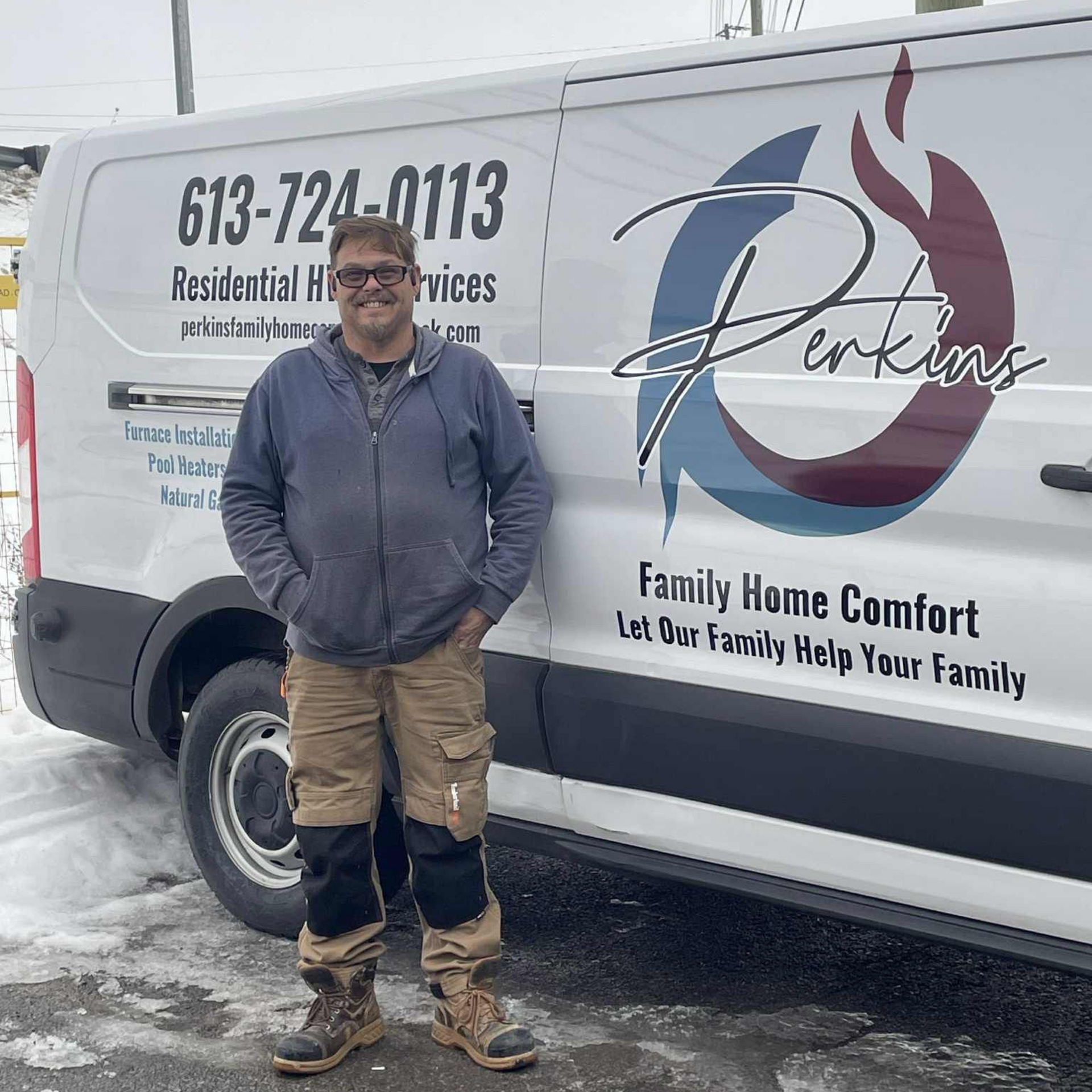 Man in work clothes standing by a white van with