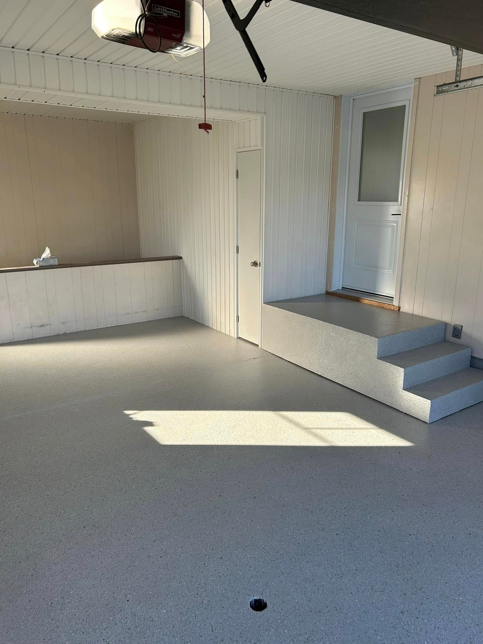 Garage vide avec sol moucheté, comptoir intégré et petite estrade surélevée avec marches.