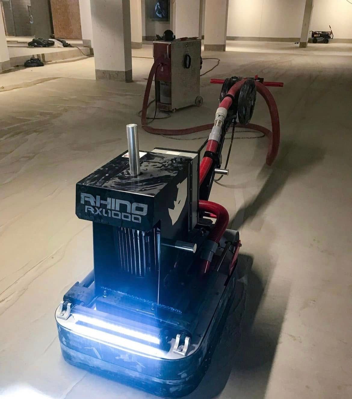 Robot de nettoyage autonome rouge avec des lumières bleues vives sur un sol de garage en béton