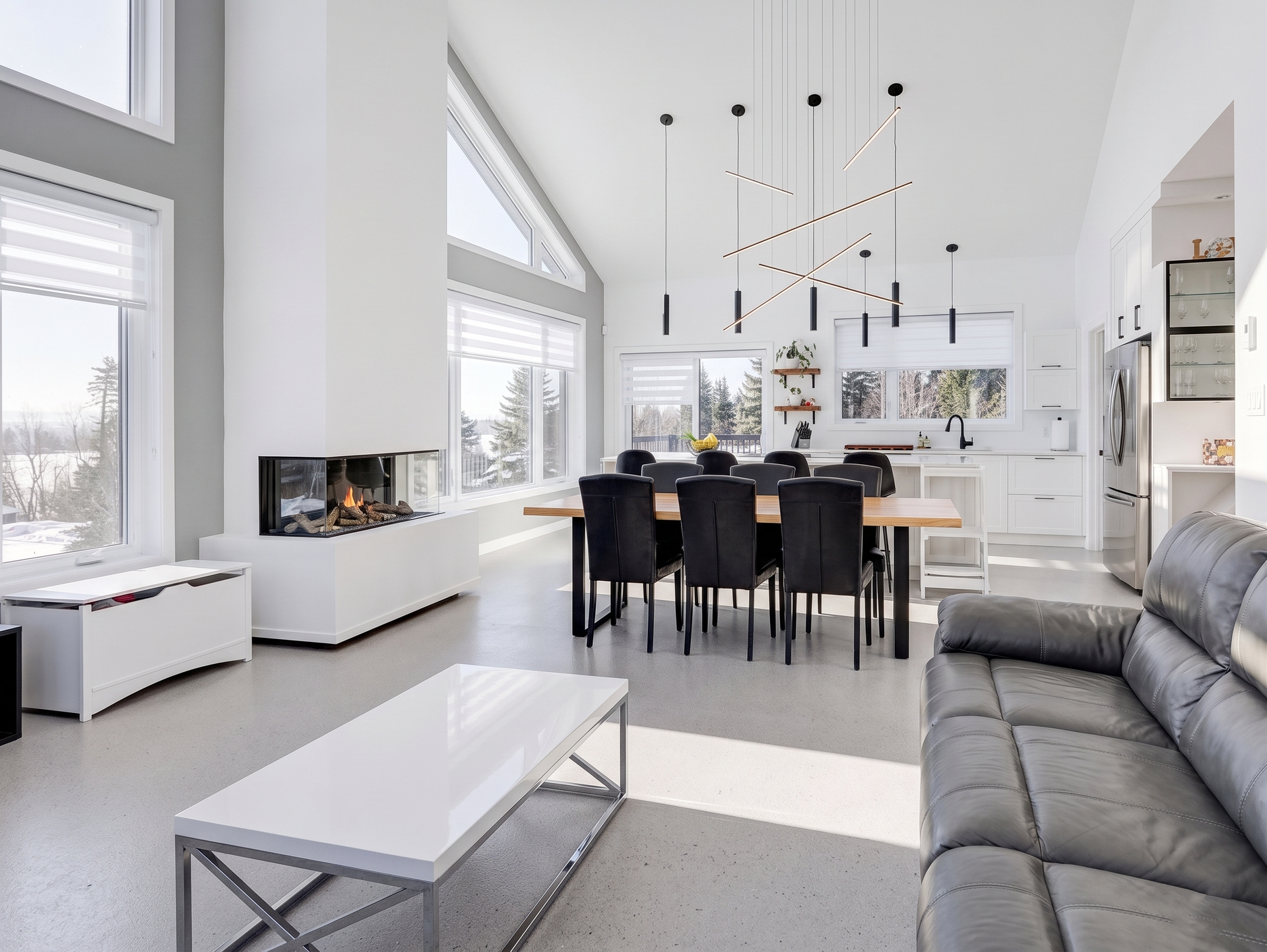 Salon et salle à manger modernes à aire ouverte avec canapé gris, décoration blanche et grandes fenêtres